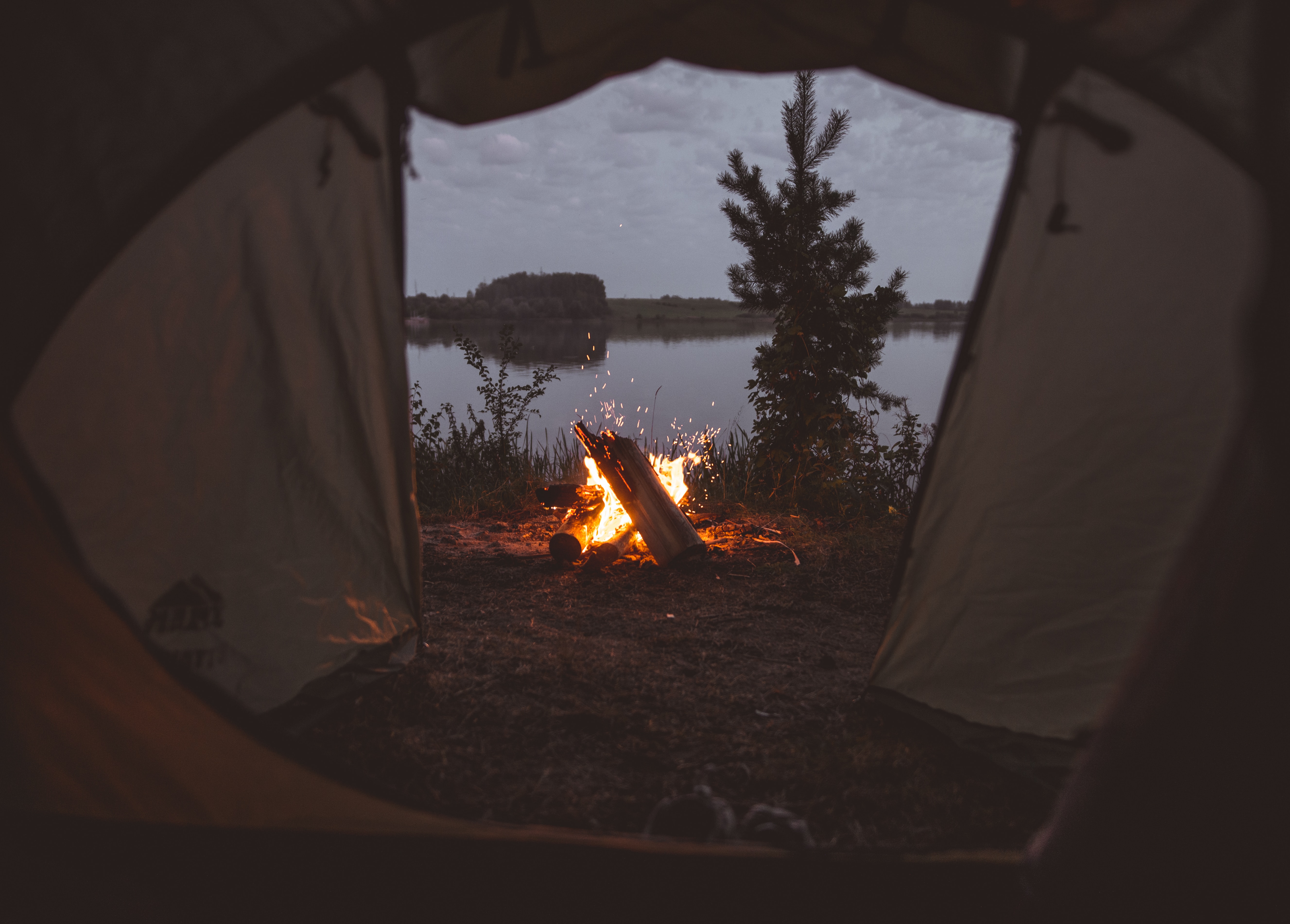 Lagerfeuer am Wasser vor dem Zelt abends
