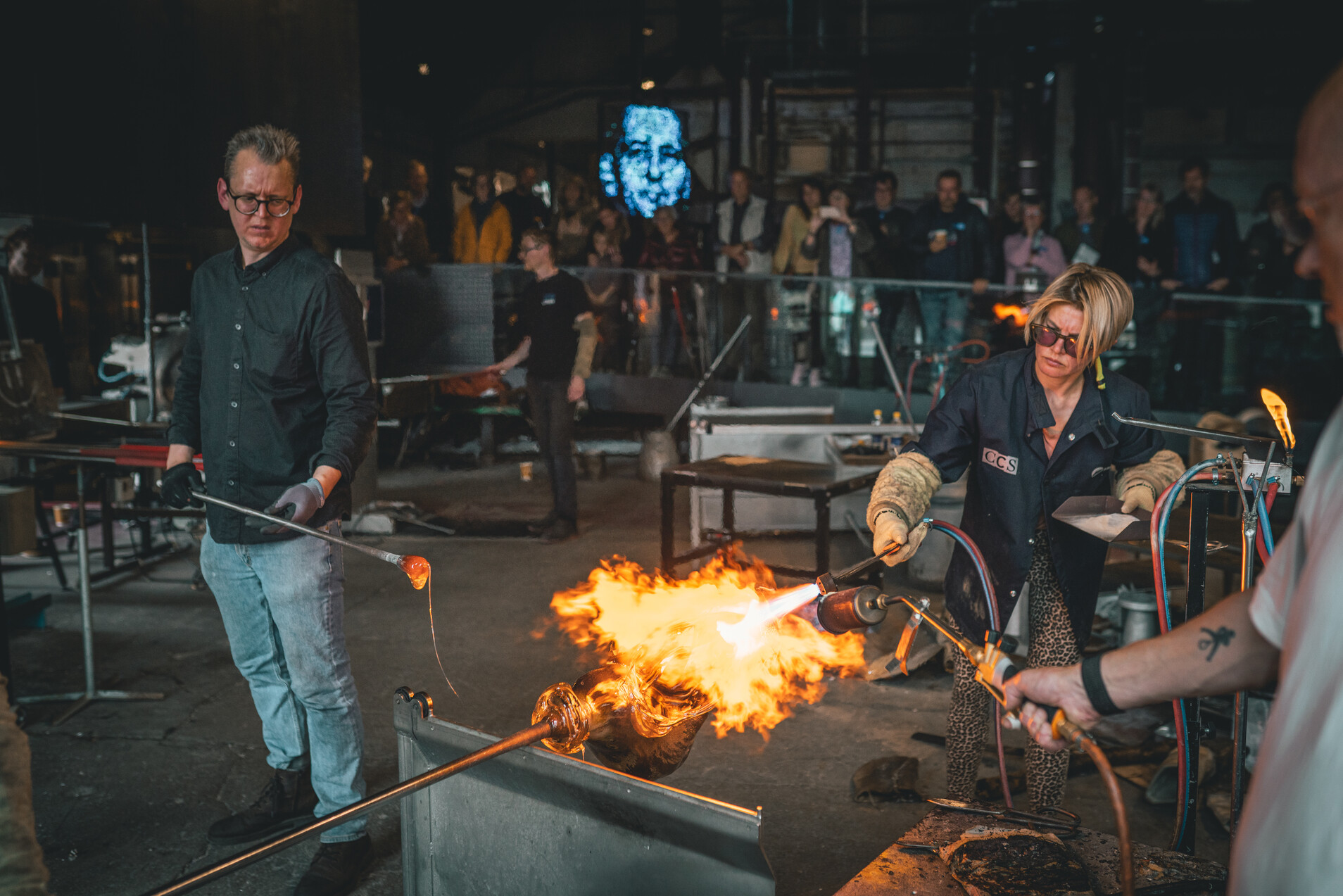 Frau und Mann produzieren mit Feuer das Glas im Holmegaard Vaerk Museum