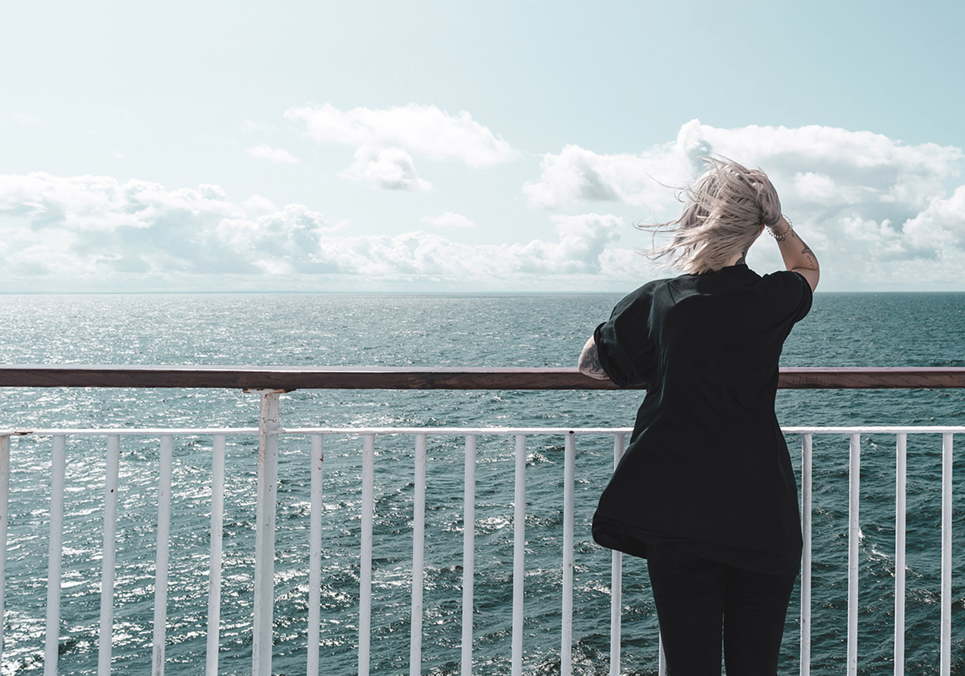 Kvinde på færgens dæk ser ud over havet og himlen