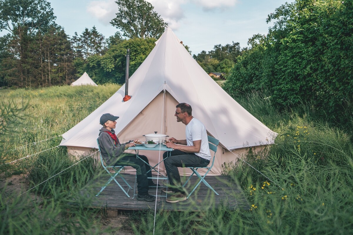 Menschen essen vor dem Zelt auf dem Campingplatz in Dänemark