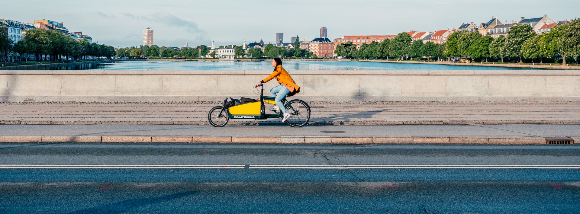Frau auf dem Lastenrad fährt über die Brücke in Kopenhagen
