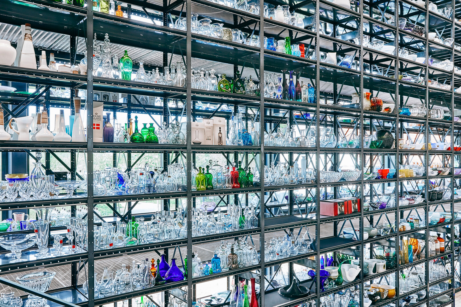 Auf die Regalen stehen bunte Glaskunstwerke im Glaswerkstatt im Holmegaard Værk Museum