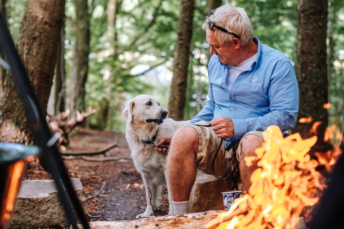 Mensch mit dem Hund beim Feuerstelle auf dem Campingplatz in Dänemark