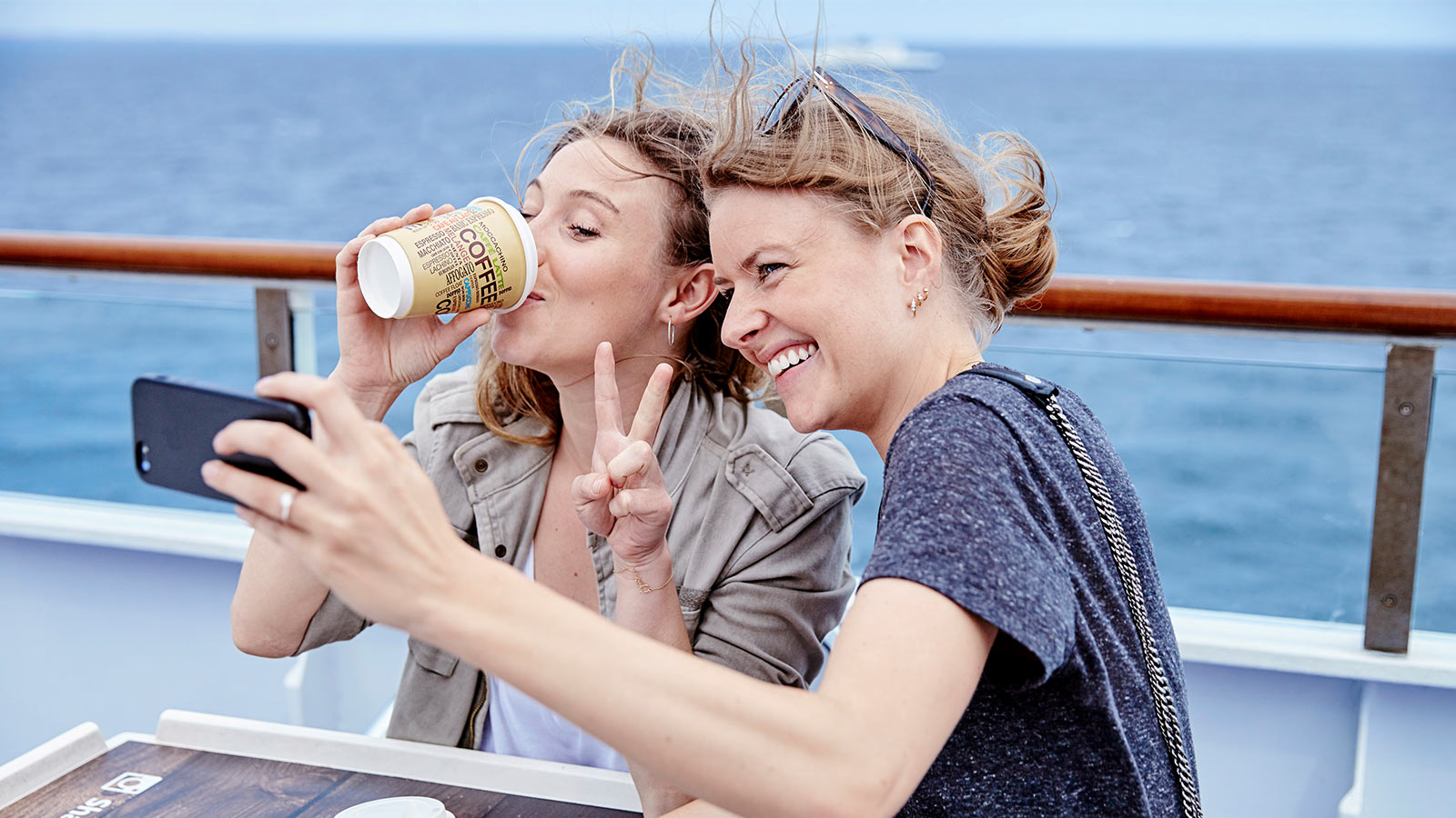 Kvinder på færgen, der drikker kaffe og tager selfies