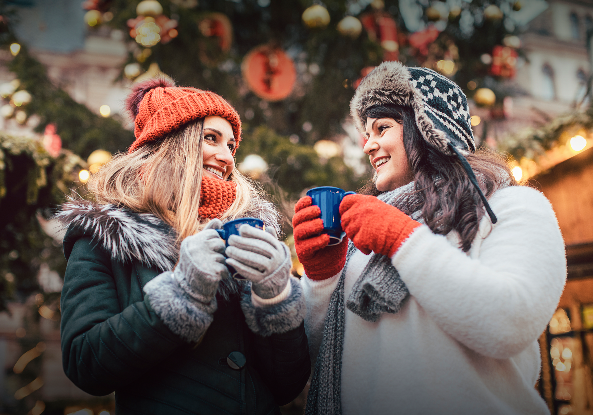 To unge kvinder drikker gluhwein på julemarked i Tyskland