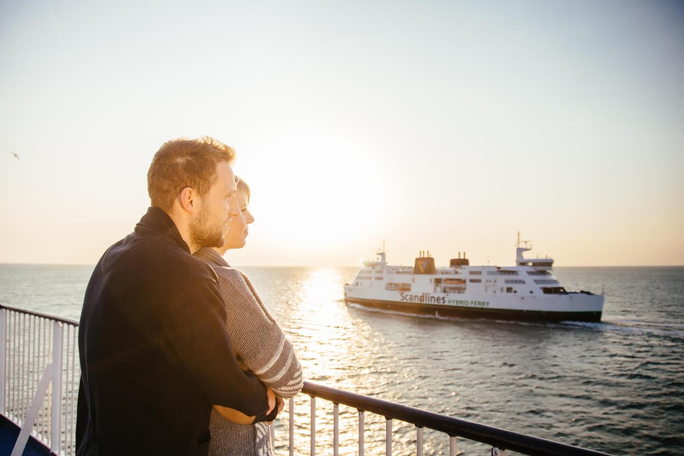 Sonnenuntergang - ein Paar guckt an Bord der Scandlines Fähre auf die Ostsee und die andere Hybridfähre von Scandlines