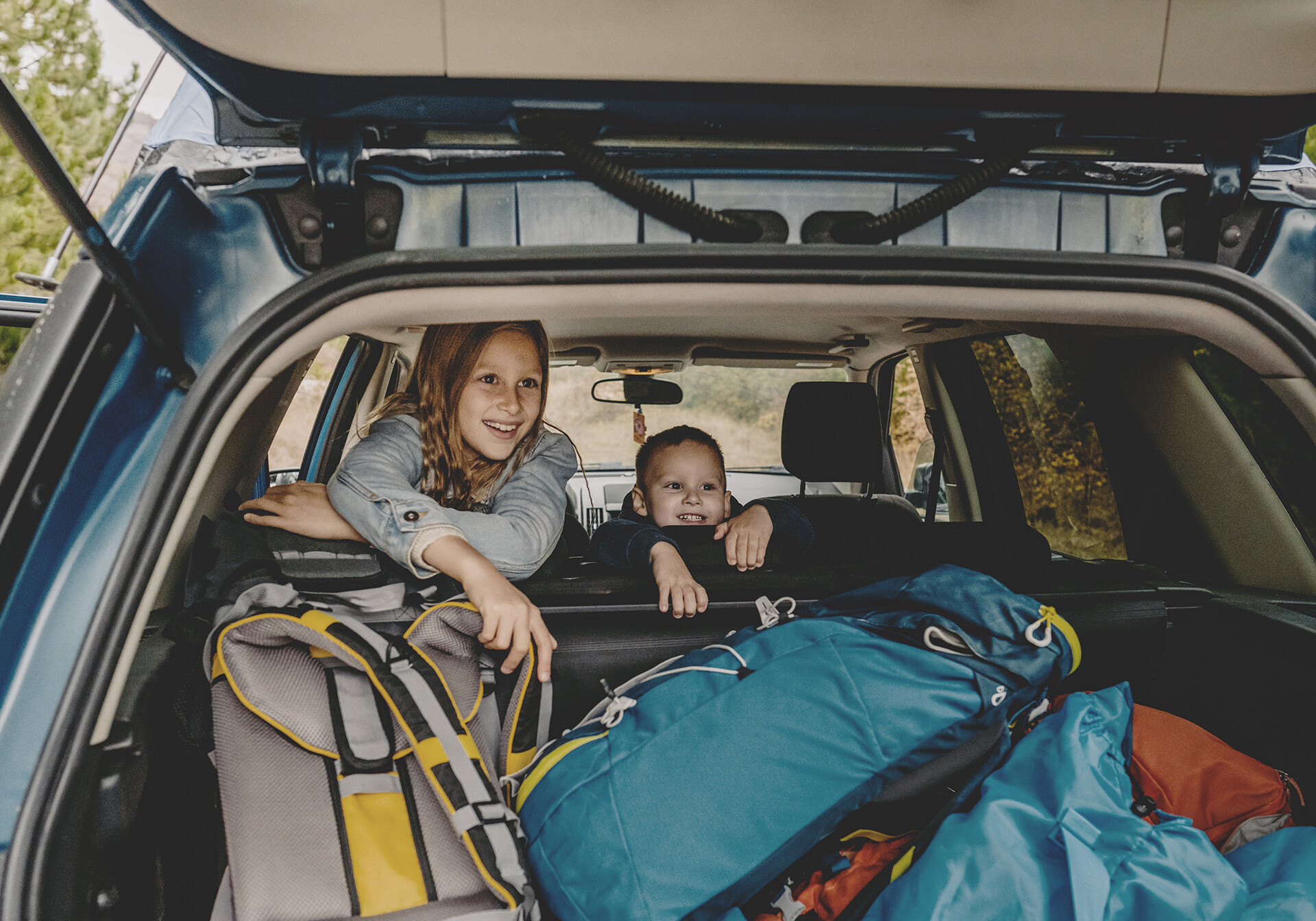 Kids in car looking out of trunk from family vacation